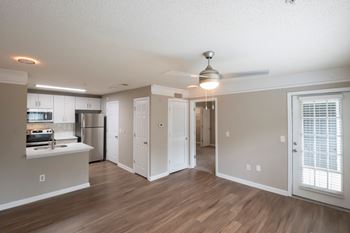A spacious kitchen with a ceiling fan and wooden floors.